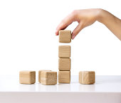 Stack wooden cubes.Hand establishes block tower isolated.