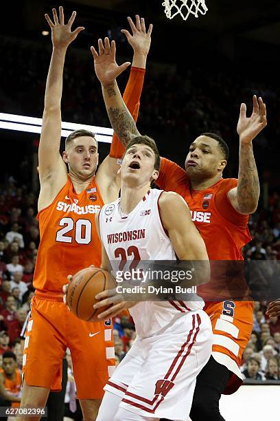 Ethan Happ of the Wisconsin Badgers handles the ball while being guarded by Tyler Lydon and DaJuan Coleman of the Syracuse Orange in the first half...