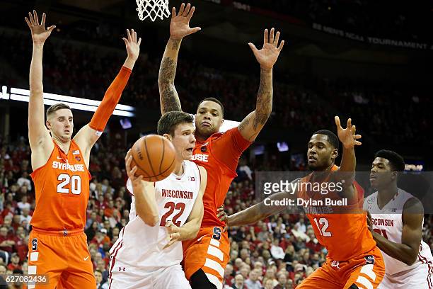 Ethan Happ of the Wisconsin Badgers passes the ball while being guarded by Tyler Lydon, DaJuan Coleman, and Taurean Thompson of the Syracuse Orange...