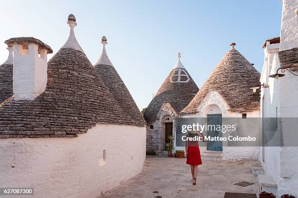 woman walking near trulli houses, alberobello, apulia, italy - alberobello stock-fotos und bilder