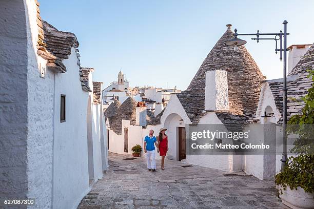 couple visiting the trulli, alberobello, apulia, italy - trulli photos et images de collection