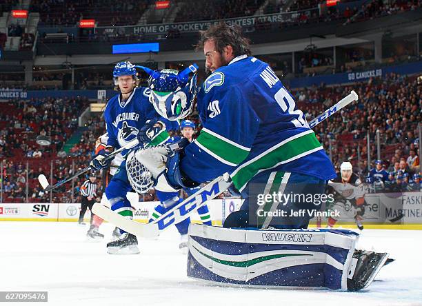 Philip Larsen of the Vancouver Canucks watches as a shot knocks the helmet off Ryan Miller of the Canucks during their NHL game against the Anaheim...