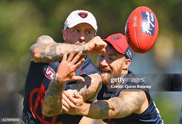 Nathan Jones of the Demons handballs whilst being tackled by Dean Kent of the Demons during the Melbourne Demons AFL pre-season training session at...