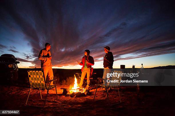 three friends handing out at a campfire. - off the beaten path foto e immagini stock