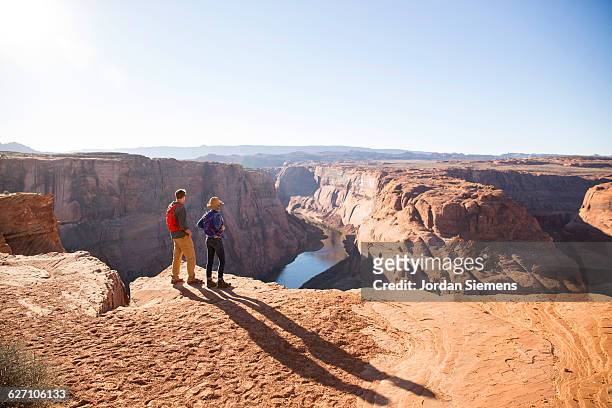 a couple hiking on the edge of a senic overlook. - grand canyon - fotografias e filmes do acervo