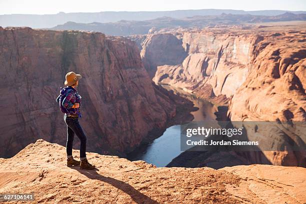 a woman hiking on the edge of a senic overlook. - grand canyon stock pictures, royalty-free photos & images