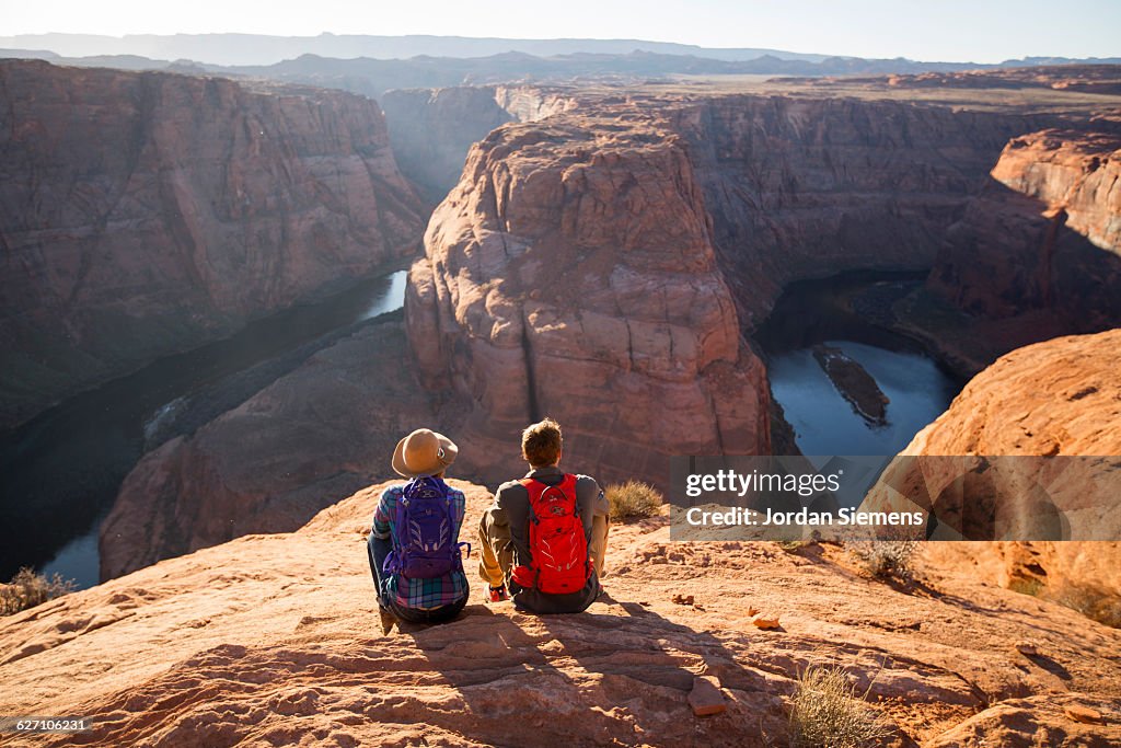 A couple hiking on the edge of a senic overlook.