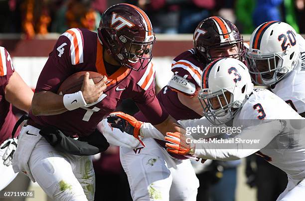 Quarterback Jerod Evans of the Virginia Tech Hokies carries the ball as safety Quin Blanding of the Virginia Cavaliers attempts the tackle in the...