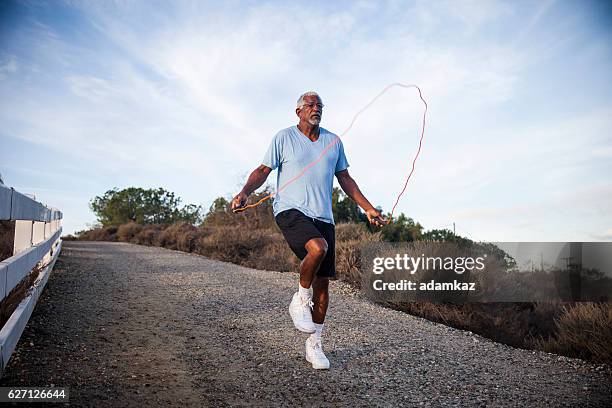 senior black man jumping seil im freien - seilspringen stock-fotos und bilder