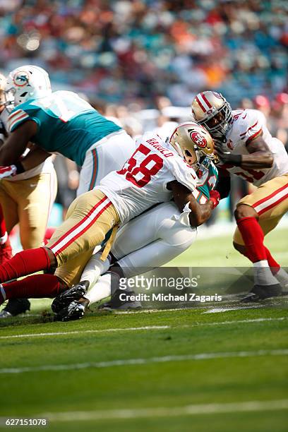 Eli Harold and Gerald Hodges of the San Francisco 49ers tackle Jay Ajayi of the Miami Dolphins during the game at Hard Rock Stadium on November 27,...