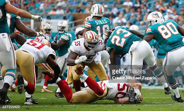 Nick Bellore and Ahmad Brooks of the San Francisco 49ers tackle Jay Ajayi of the Miami Dolphins during the game at Hard Rock Stadium on November 27,...