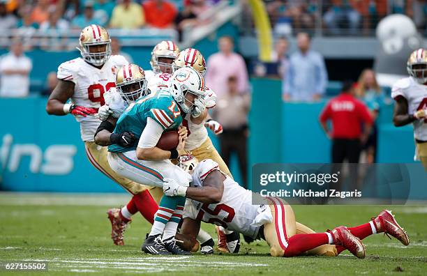 Ahmad Brooks, Nick Bellore and Gerald Hodges of the San Francisco 49ers tackle Ryan Tannehill of the Miami Dolphins during the game at Hard Rock...