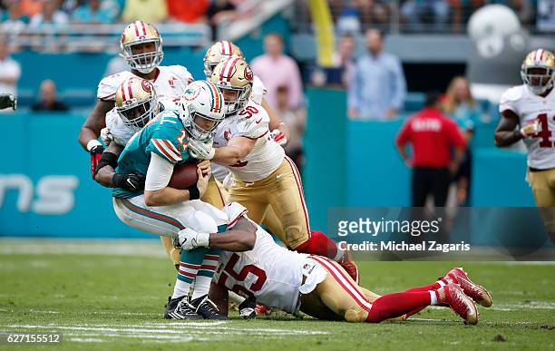 Ahmad Brooks, Nick Bellore and Gerald Hodges of the San Francisco 49ers tackle Ryan Tannehill of the Miami Dolphins during the game at Hard Rock...
