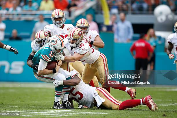 Ahmad Brooks, Nick Bellore and Gerald Hodges of the San Francisco 49ers tackle Ryan Tannehill of the Miami Dolphins during the game at Hard Rock...