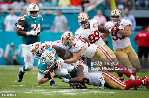 Ahmad Brooks, Nick Bellore and Gerald Hodges of the San Francisco 49ers tackle Ryan Tannehill of the Miami Dolphins during the game at Hard Rock...