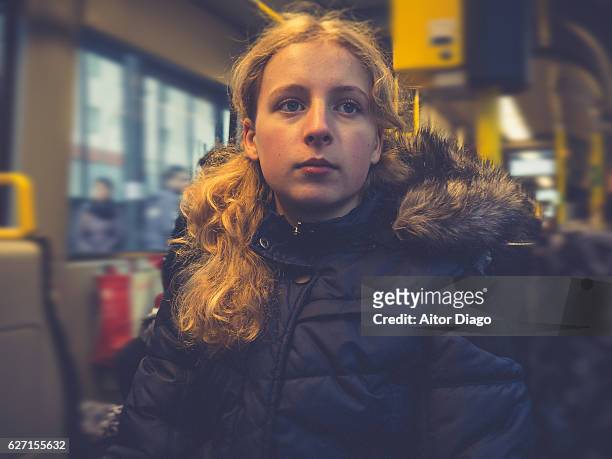 Pensive girl (13-14 years)  sitting on a tram wagon.
