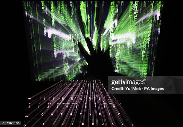 Zoom burst photo of a user touching the screen of a laptop displaying a 'Matrix'-style screensaver, in London