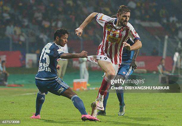 Atletico de Kolkata forward Juan Belencoso runs past FC Pune City defender Narayan Das during the Indian Super League football match between Atletico...