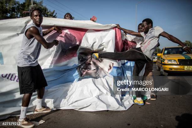 Supporter of the newly elected Gambia's President Adama Barrow kick a poster of the incumbent Yahya Jammeh in Serekunda on December 2, 2016....