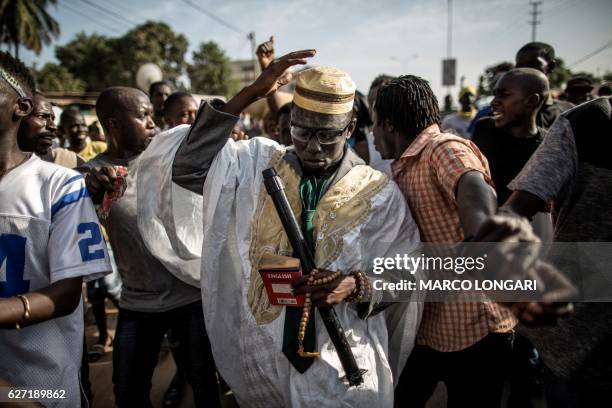 Man dressed like incumbent president Yahya Jammeh parades with supporters of the newly elected president Adama Barrow as they celebrate his victory...