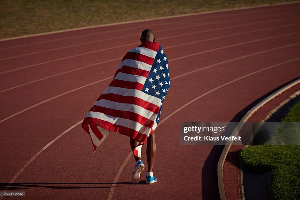 Athlete walking away from camera with flag