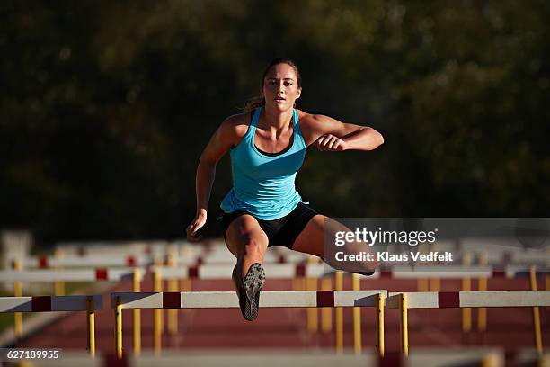 female athelete jumping over hurdle at sunrise - barreira imagens e fotografias de stock