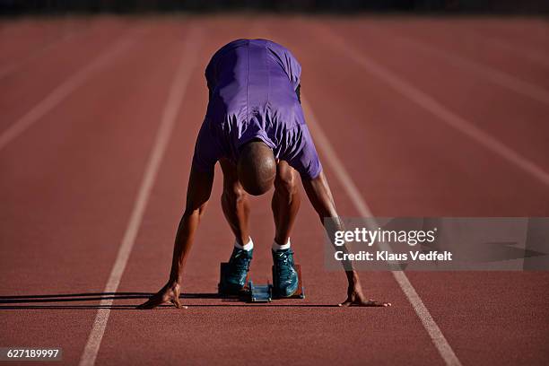 male runner ready in start block at stadium - starting block photos et images de collection