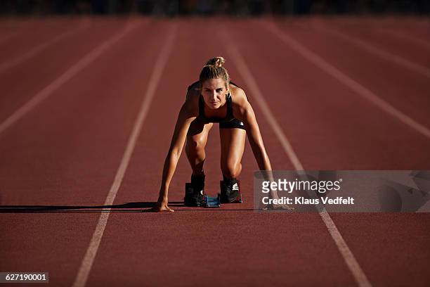 portrait of female runner in start block - leichtathletik stock-fotos und bilder