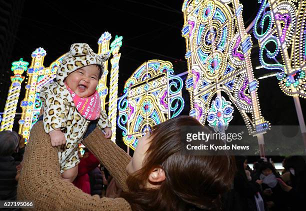 Woman lifts a baby at the Kobe Luminarie light festival, held to commemorate victims of the 1995 Great Hanshin Earthquake in the western Japan port...