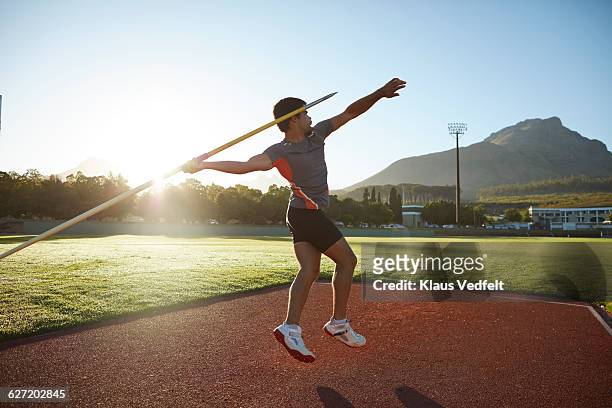 male athlete throwing javelin at stadium - speerwurf stock-fotos und bilder