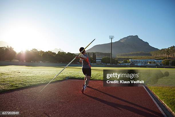 male athlete throwing javelin at stadium - javelin stock-fotos und bilder