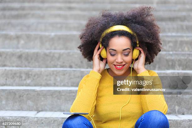 donna con cuffie gialle che ascolta musica - yellow blouse foto e immagini stock