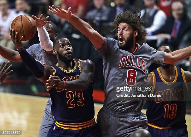 LeBron James of the Cleveland Cavaliers puts up a shot between Dwyane Wade and Robin Lopez of the Chicago Bulls at the United Center on December 2,...