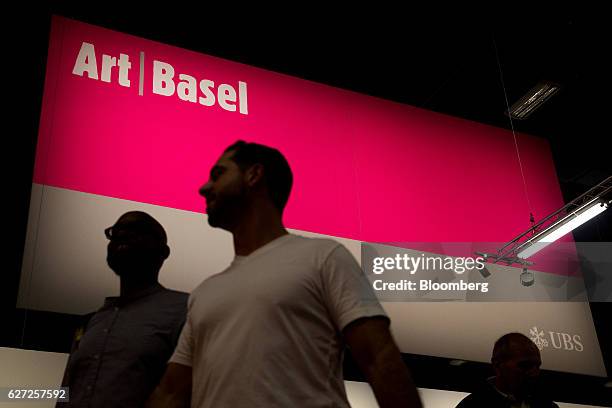 Visitors walk past the signage for Art Basel at Art Basel Miami Beach in Miami, Florida, U.S., on Friday, Dec. 2, 2016. Politics is prevalent at Art...