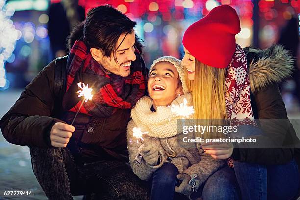 young couple is hugging their daughter at xmas - mother and daughter on night street stockfoto's en -beelden