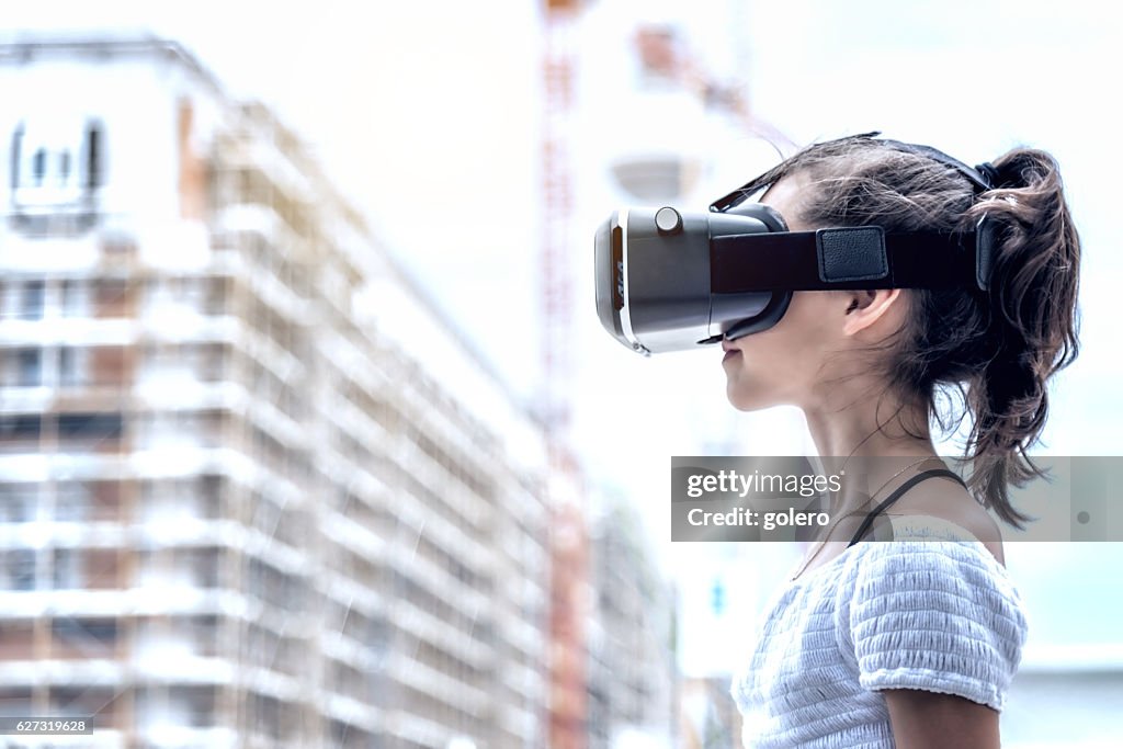 Girl with virtual reality simulator with blurred city background