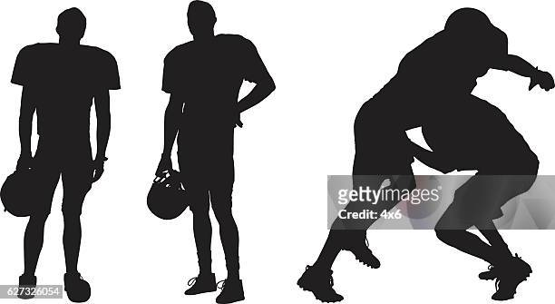 american football player standing and tackling - american football player silhouette stock illustrations