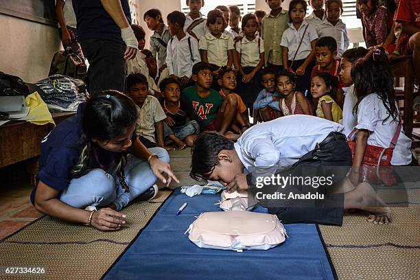 Chan Sovanna from Safety When It Matters Cambodia instructs a student how to perform CPR on a mannequin during a water safety and drowning prevention...