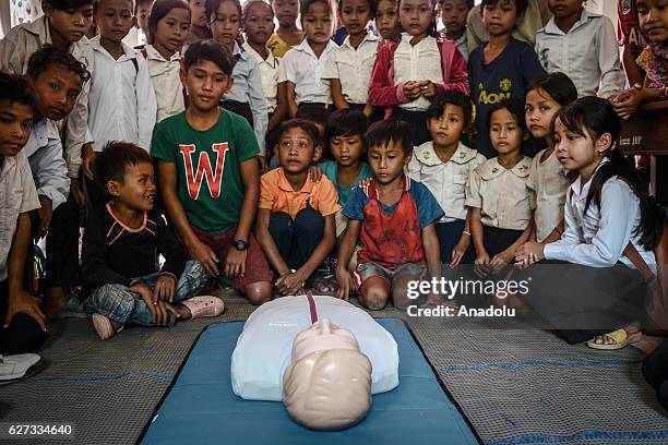 Children look at a CPR mannequin during a water safety and drowning prevention class on Monday, November 28, 2016 in Prey Veng province.