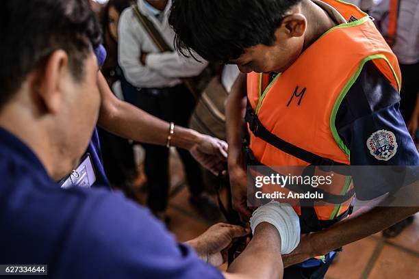 Keo Sopheap and Chan Sovanna from Safety When It Matters Cambodia help a student put on a life jacket during a safety and drowning prevention class...