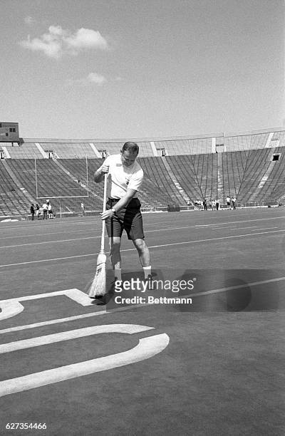 Michigan coach Bo Schembechler proves that lawnmowers are a thing of the past at the University football stadium 8/26 as he sweeps clean the...