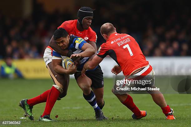 Ben Tapuai of Bath is held up by Maro Itoje and Schalk Burger of Saracens during the Aviva Premiership match between Bath Rugby and Saracens at the...