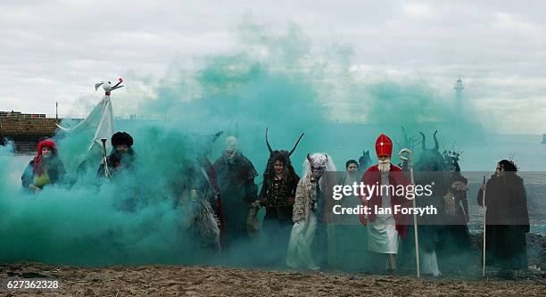 Green smoke is released as participants dressed as the folklore figure, Krampus, and other characters pose for pictures on the beach in Whitby ahead...