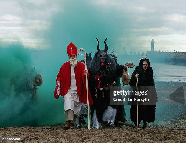 Green smoke is released as participants dressed as the folklore figure, Krampus, and other characters pose for pictures on the beach in Whitby ahead...