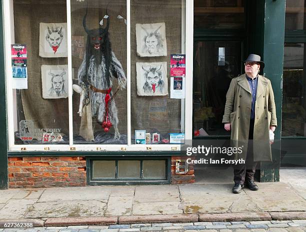 Man stands next to a window display showing the folklore figure, Krampus, ahead of a charity event on December 3, 2016 in Whitby, United Kingdom. The...