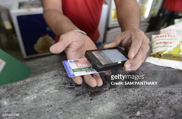 Staff member scans a prepaid smart card at a Mother Dairy store, at Bhatt village on the outskirts of Ahmedabad, on December 3, 2016. - Amul in...