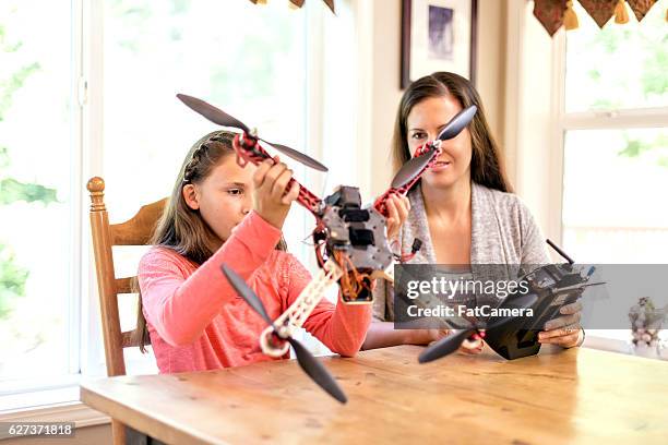 young girl and mother looking at a drone and controller - quadcopter stock pictures, royalty-free photos & images