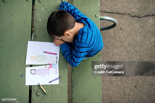 young boy looking sad at drawing of a broken family - divorce stock pictures, royalty-free photos & images