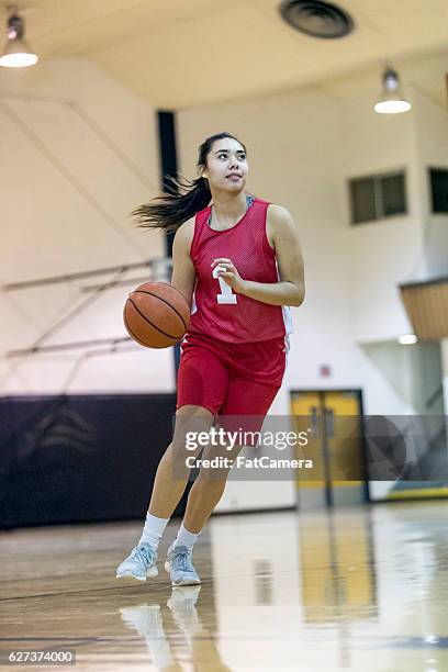 ethnic female high school basketball player dribbling ball - charging sports stockfoto's en -beelden