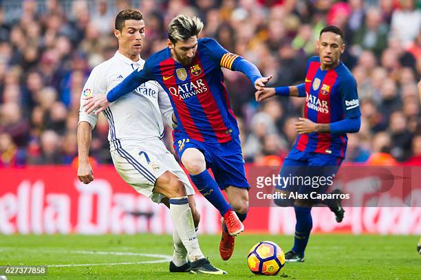 Lionel Messi of FC Barcelona conducts the ball next to Cristiano Ronaldo of Real Madrid CF during the La Liga match between FC Barcelona and Real...